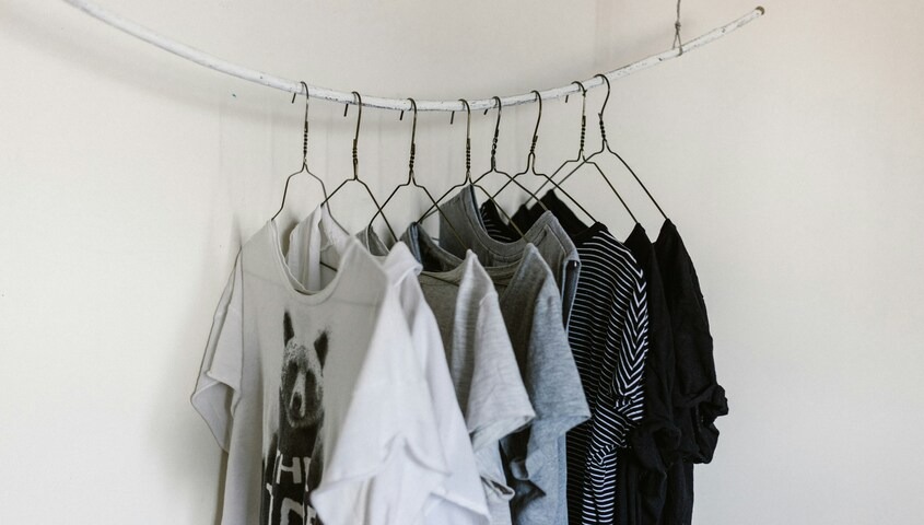 A curated collection of fashion-forward blanks on a rack, highlighting the importance of fabric weight and silhouette when learning how to design a shirt.