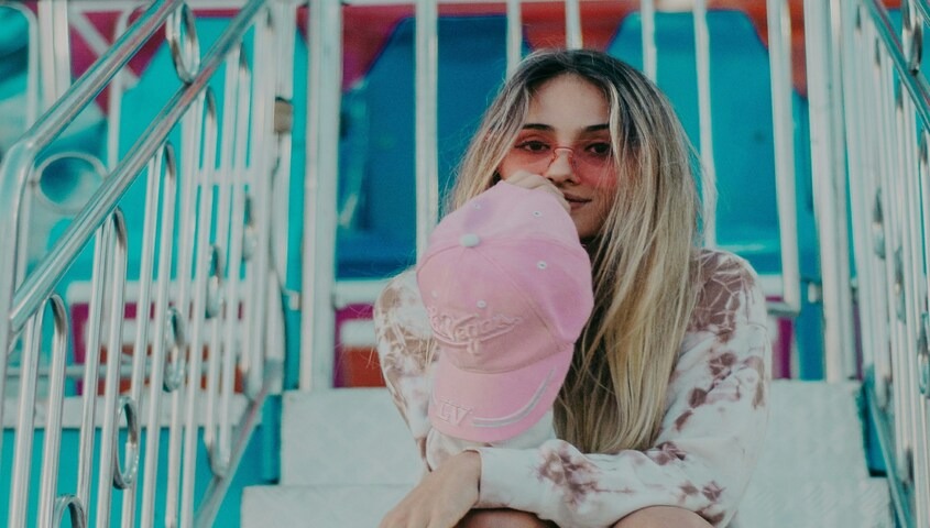 Young woman in pink cap and tie-dye top inspired by female 90s fashion trends and iconic 90s outfits