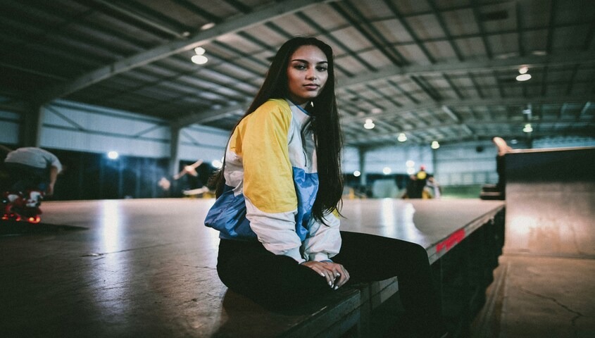 Woman in retro colorblock jacket at skatepark showcasing authentic 90s outfits and streetwear style