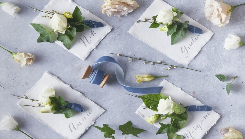 Handwritten wedding place cards with florals and blue velvet ribbon, a category within top selling etsy items.