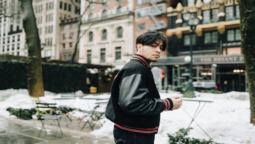 Man in black and red varsity jacket on a snowy NYC street, classic late 90s fashion silhouette
