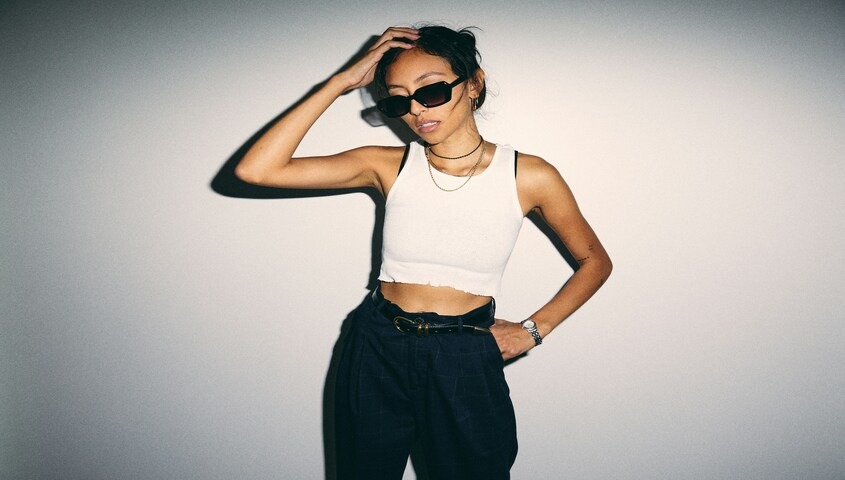 Woman in a white cropped tank and dark trousers showing the 90s baby tee outfit aesthetic