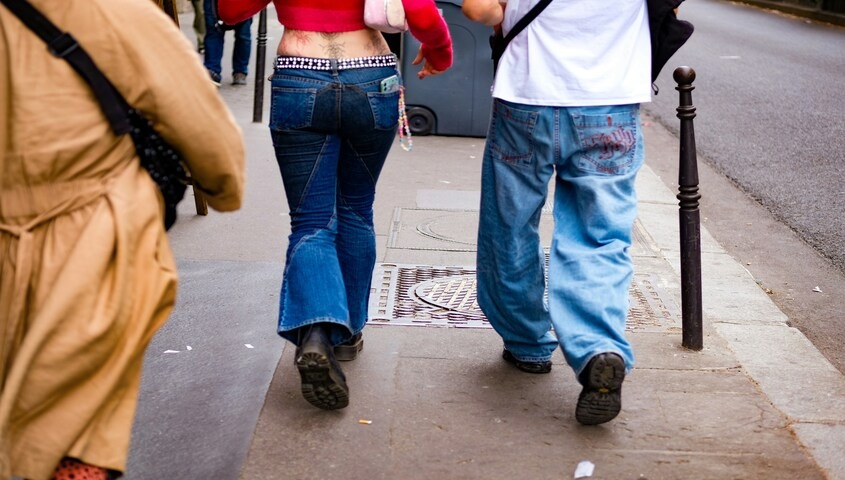 Two people walking in flared and baggy low-rise jeans, a defining 90s outfit moment on the street