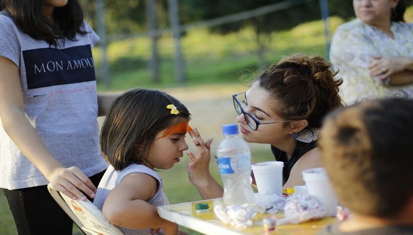 Stay at home mom face painting children at an in-home daycare, a high-leverage side hustle for stay at home moms with kid-friendly homes