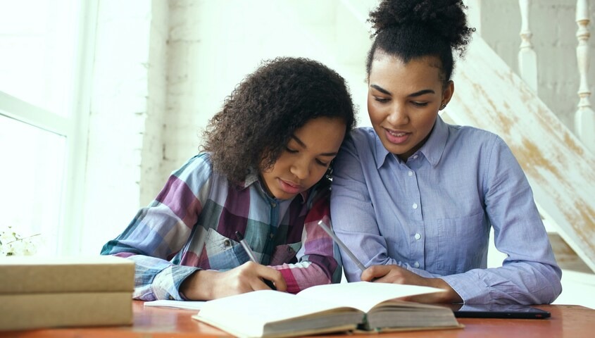 Teen tutoring a younger student at a table, showing how to make money as a teen.