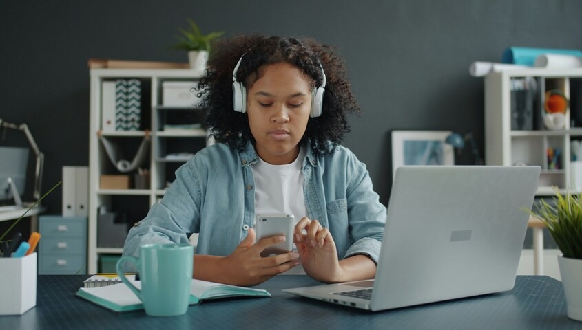 Teenager at a desk with a laptop and phone exploring business ideas for teens to make money.