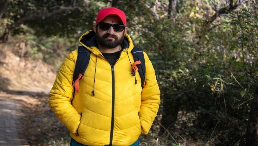 Man wearing a yellow puffer jacket and cap outdoors showing everyday gorpcore style.