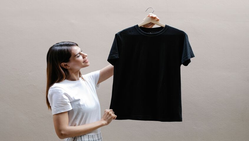 Woman holding a polyester tee on a hanger, illustrating does polyester stretch in everyday wear