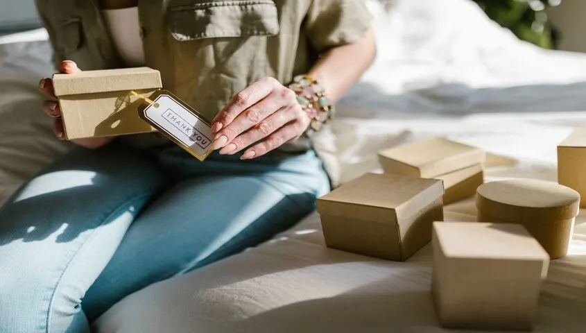 Etsy seller packing orders into boxes with a thank you tag, ready to ship using discounted Etsy shipping label fees