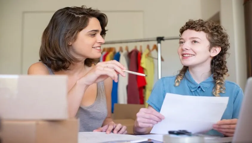 Two Etsy sellers reviewing paperwork together, working out how much money does Etsy take from sellers