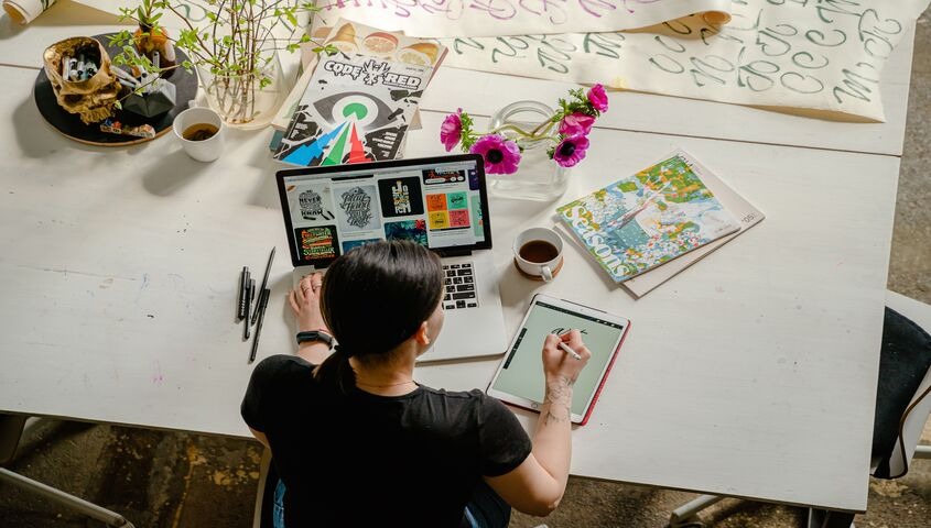 Artist working on original artwork at a desk, showing how do artists make money selling one-of-one pieces online.