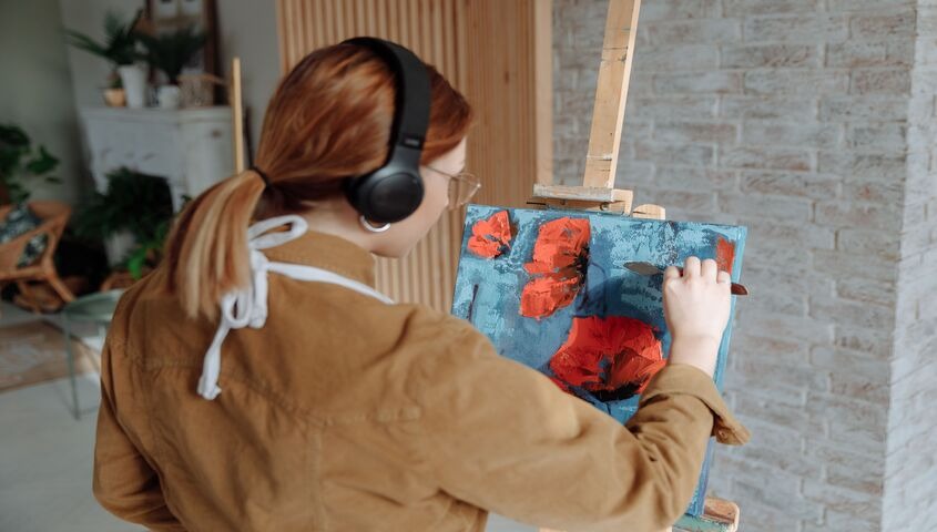 Painter working on a canvas in a home studio, applying the tips that separate real earners from beginners learning how to make money as an artist.