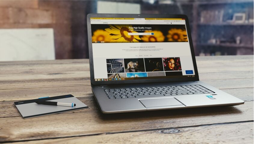 Laptop on a wooden desk showing a finished website homepage, the end result of the Wix vs Squarespace decision