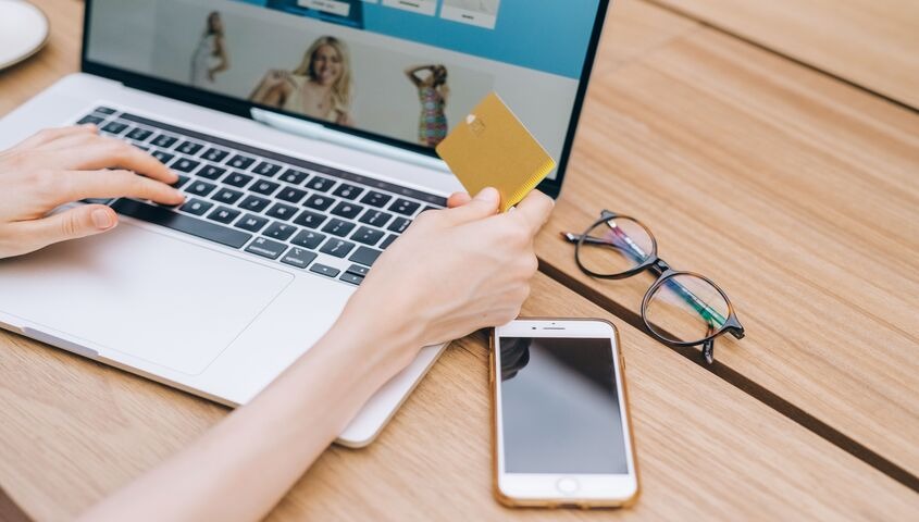 Customer holding a credit card at a laptop, checking out on a fashion store built to boost ecommerce sales
