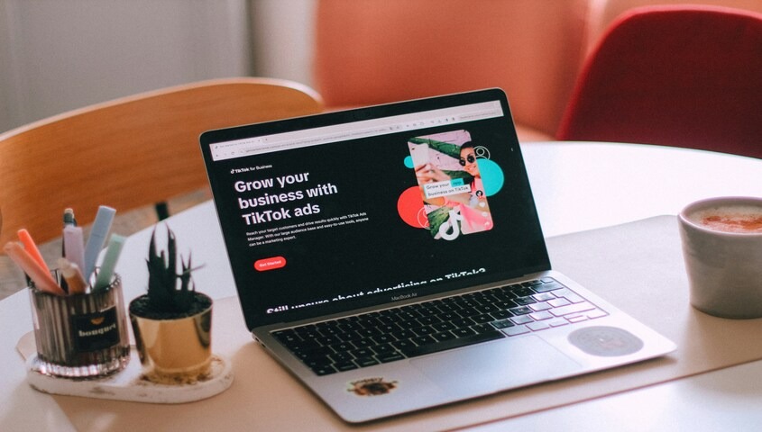 Laptop on a cafe table open to a TikTok for Business page, where posting time drives TikTok engagement