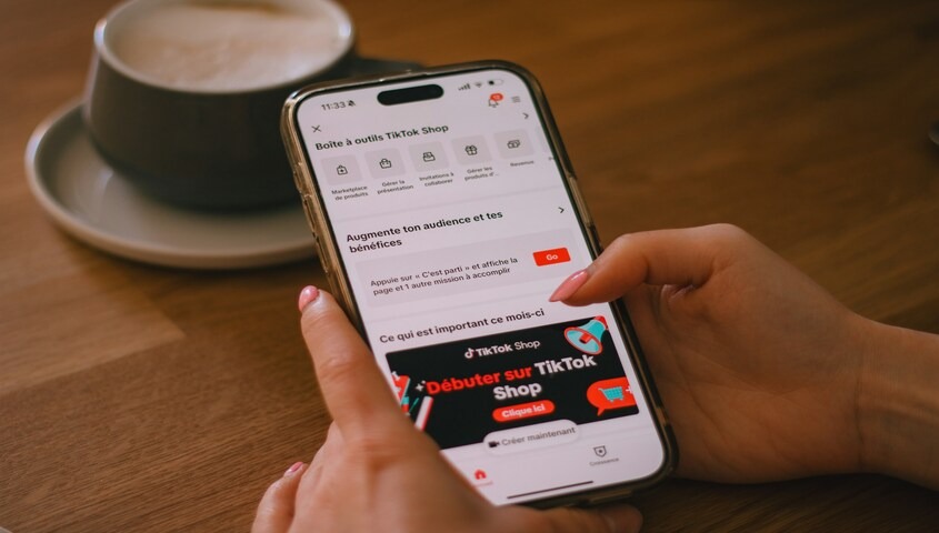 Hand tapping through the TikTok app over coffee, finding a personal best time to post on TikTok