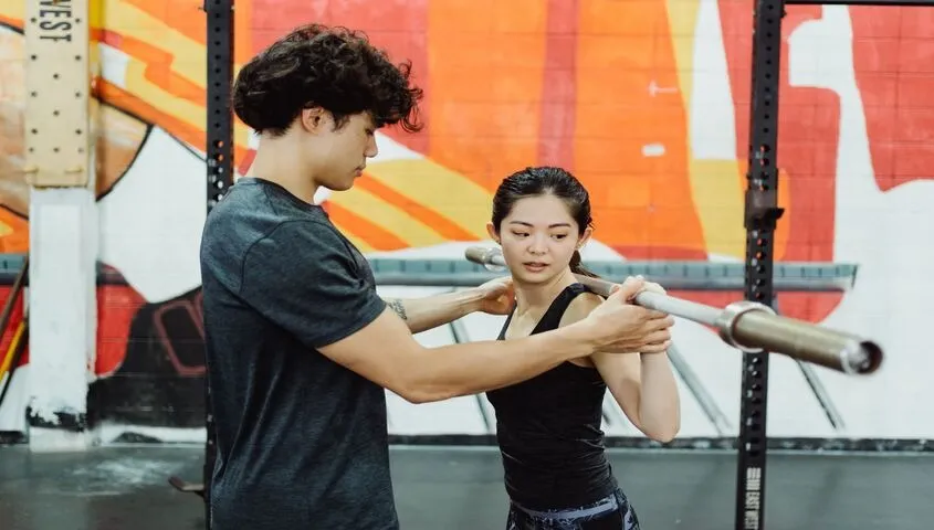 Personal trainer coaching a client's form in a gym, one of the higher-margin low cost business ideas with no physical product.