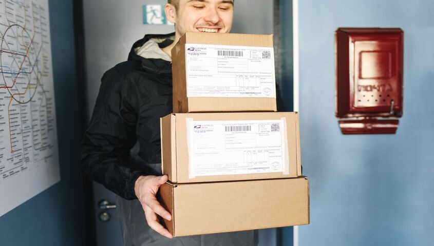 Founder holding a stack of shipping packages, showing dropshipping as one of the best business to start with little money options in 2026.