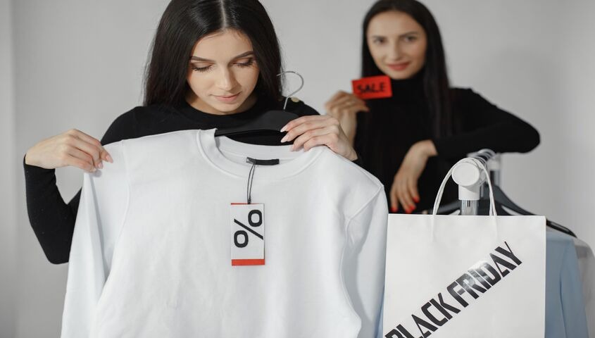 Two shoppers picking up a white sweatshirt in a store, showing what is print on demand solving that traditional retail can't.