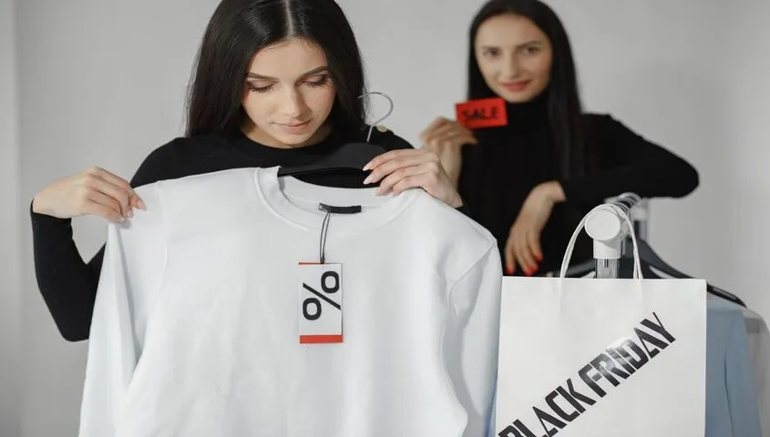 Two shoppers picking up a white sweatshirt in a store, showing what is print on demand solving that traditional retail can't.