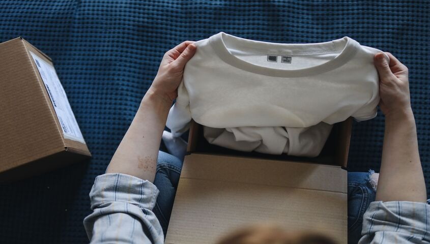 Overhead shot of a customer unboxing a print on demand shirt, showing the honest tradeoffs behind the model.