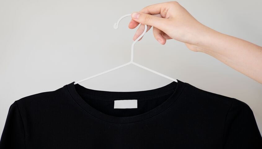 Hand holding a black tee on a hanger, showing the product-quality test that separates real free dropshipping suppliers from the rest.