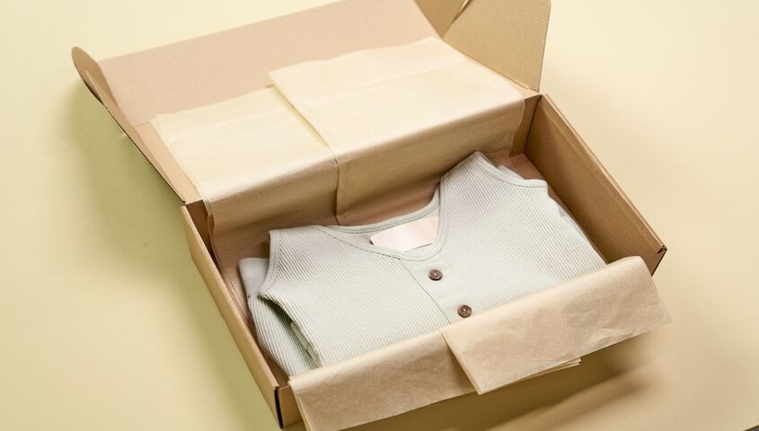 Folded knit henley in branded packaging inside a shipping box, showing why Tapstitch sits among the top dropshipping websites for founders who care about the customer experience.