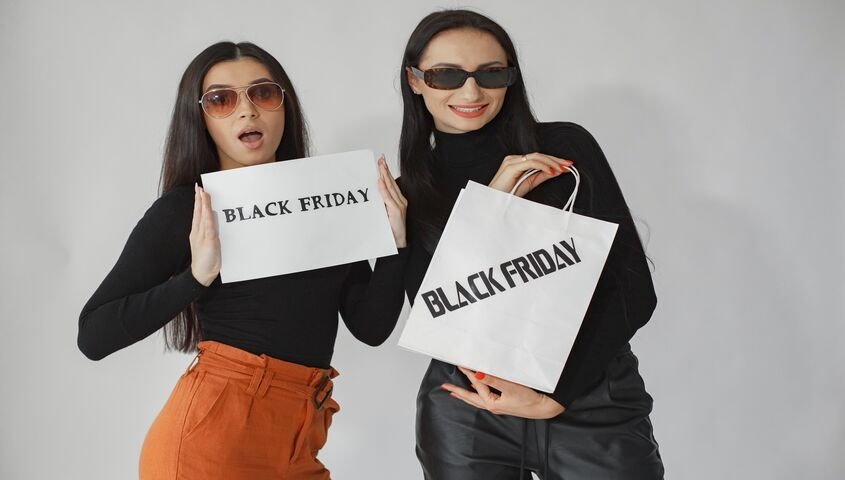 Shoppers holding Black Friday signage and a shopping bag, previewing 15 black friday marketing ideas for indie brands.