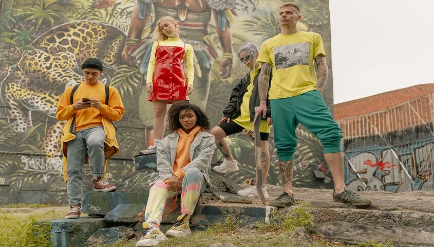 Crew in colorful streetwear posed against a mural, the fashion-grade side of print on demand trends 2026 that Tapstitch is built for.