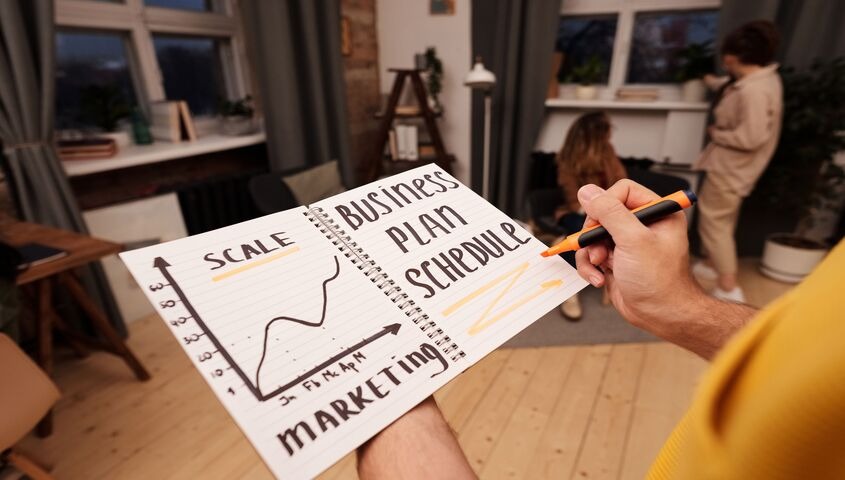Founder sketching a marketing plan in a notebook, mapping the drop-based print on demand trends shaping 2026 strategy.