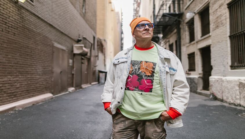 Man in an alley wearing a bold graphic tee and denim jacket, showing the heavyweight product side of print on demand trends 2026.