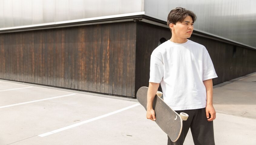 Relaxed tee worn with a skateboard on the street, the crossover fit athleisure buyers expect.