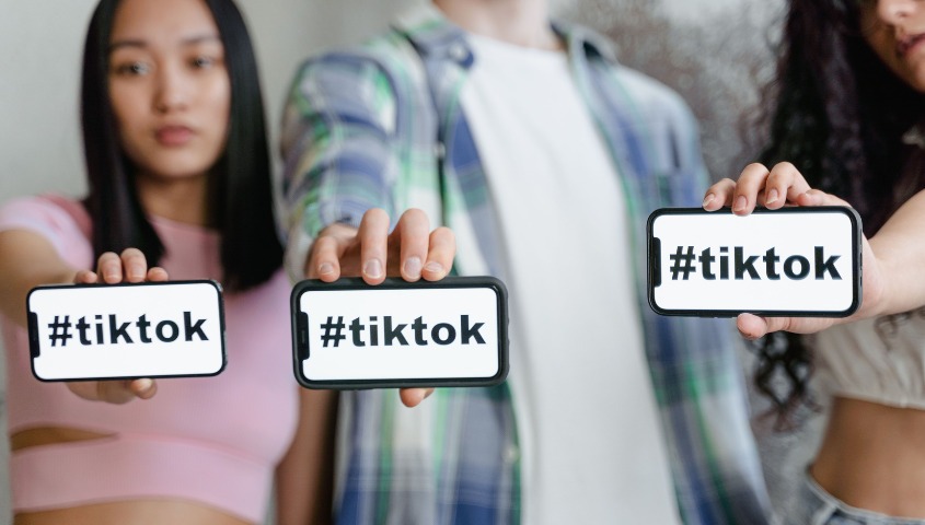 Young adults holding smartphones with TikTok hashtag