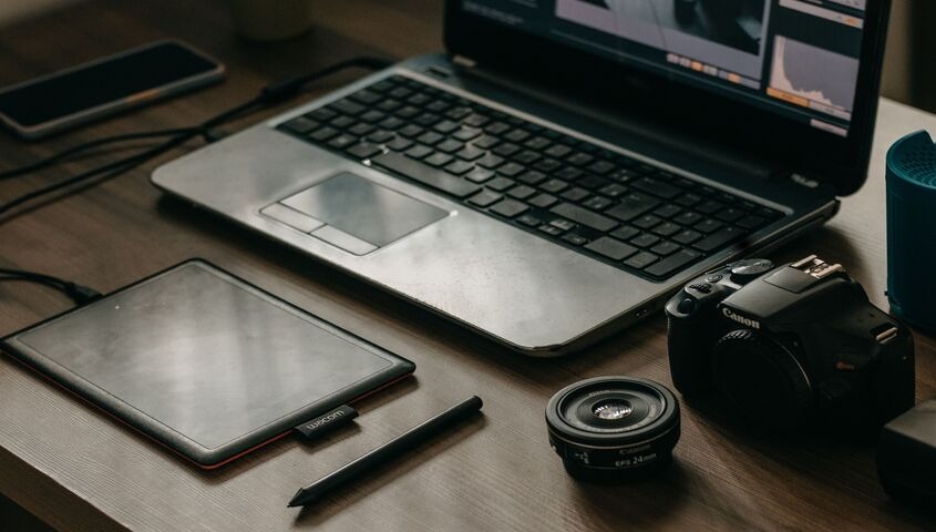 Laptop, drawing tablet and camera on a desk, the tools behind selling digital products online