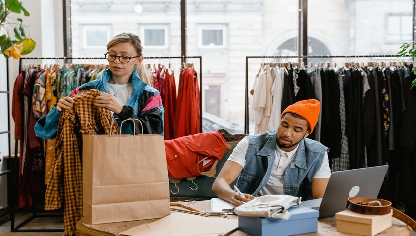 Two founders setting up product listings on a laptop, working to create online clothing store pages that sell.