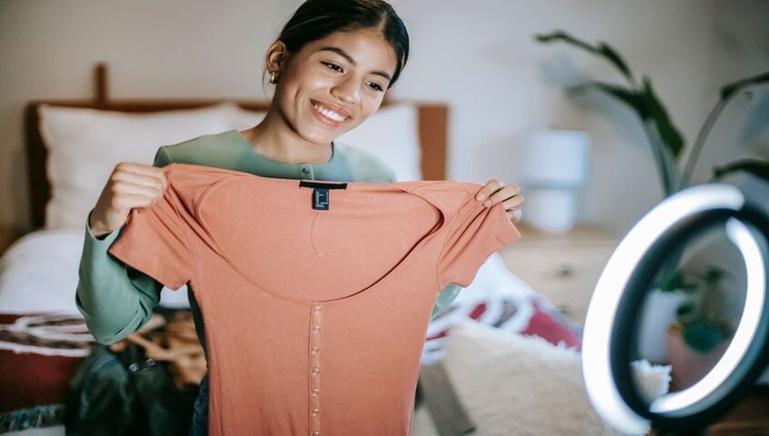 Seller showing a coral top on camera next to a ring light, the in-feed checkout that makes it possible to sell products on tiktok.