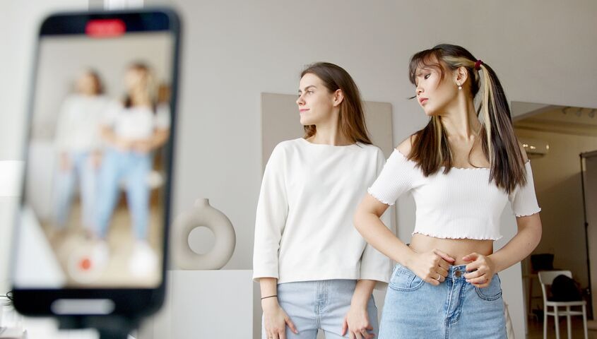 Two models filming a try-on video on a phone, the starting point for how to sell on tiktok shop in 2026.