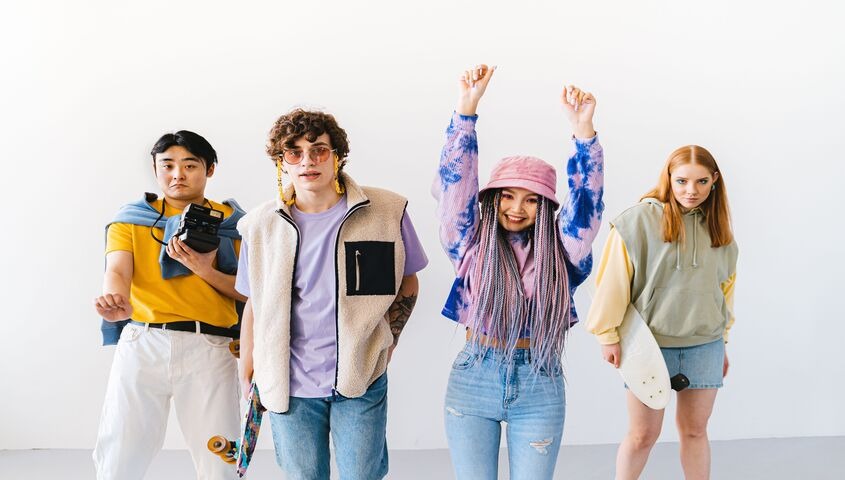 Four friends in colorful streetwear against a white wall, settling the dropshipping vs print on demand question for fashion brands.