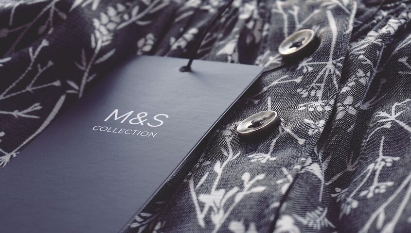Close-up of a branded hang tag on a patterned shirt, the label detail at the heart of what is branded dropshipping.