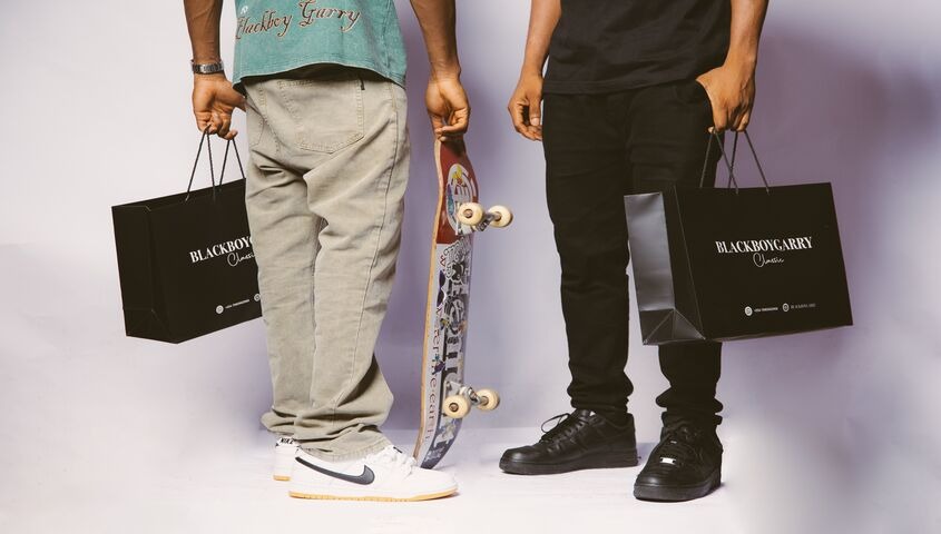 Two shoppers holding branded boutique bags with a skateboard, the branding dropshipping payoff of identity people show off.