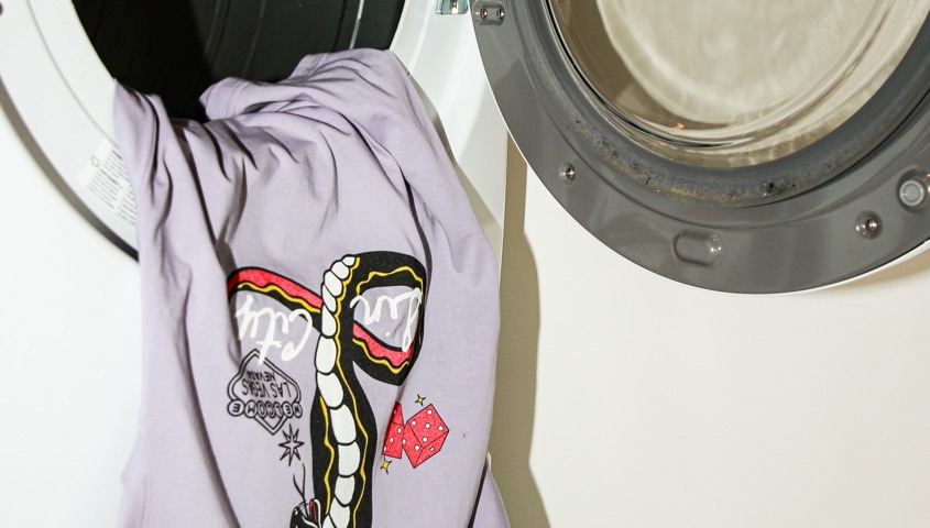 Printed lilac T-shirt hanging from a washing machine door before a wash test