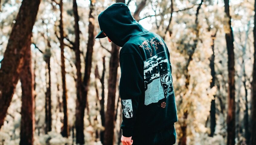 Person wearing a graphic band hoodie outdoors, the piece that carries most of the money on any merch table.