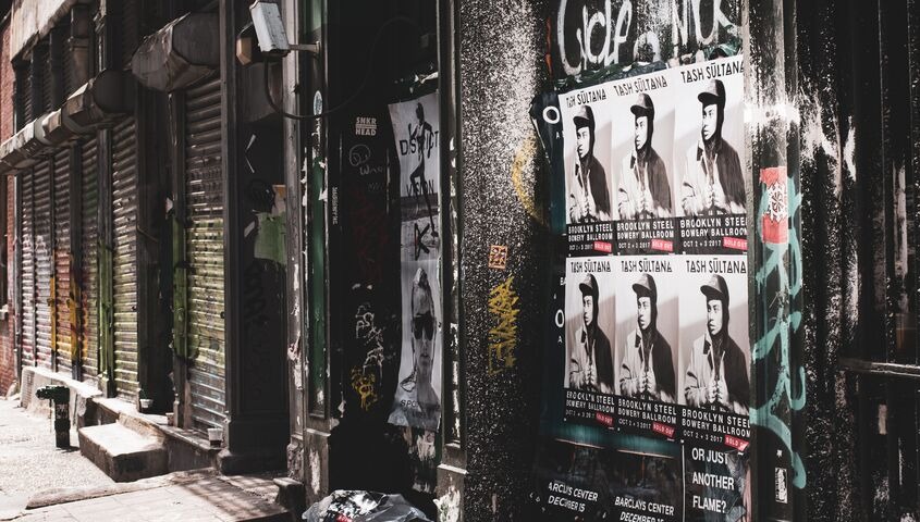 Tour posters pasted along a city street wall, the gig print that becomes one of the more collectible cool merch ideas once numbered.