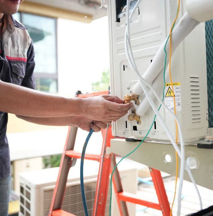 Technician working on an outdoor air conditioning unit.