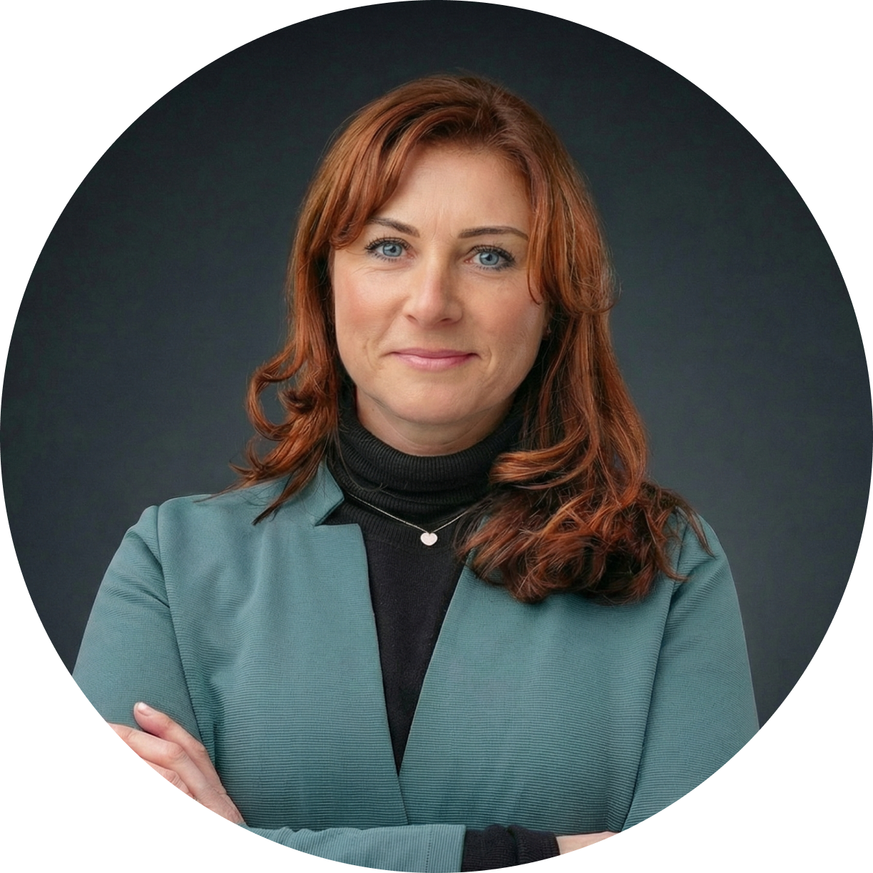 Porträt einer Frau mit roten Haaren, die eine grüne Jacke und einen schwarzen Rollkragenpullover trägt und mit verschränkten Armen in die Kamera lächelt.