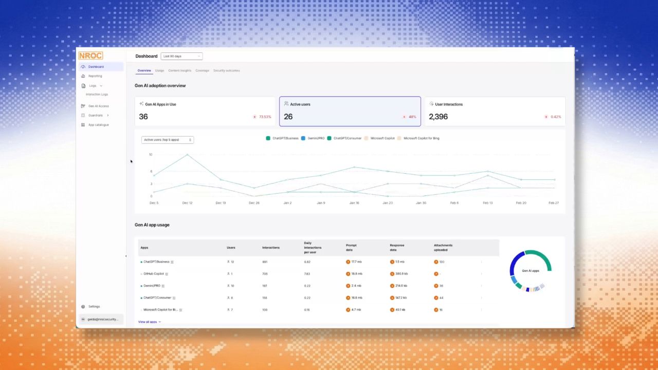Middle-aged man with short gray hair in a blue shirt speaking during a video call with a bookshelf and a lamp in the background.