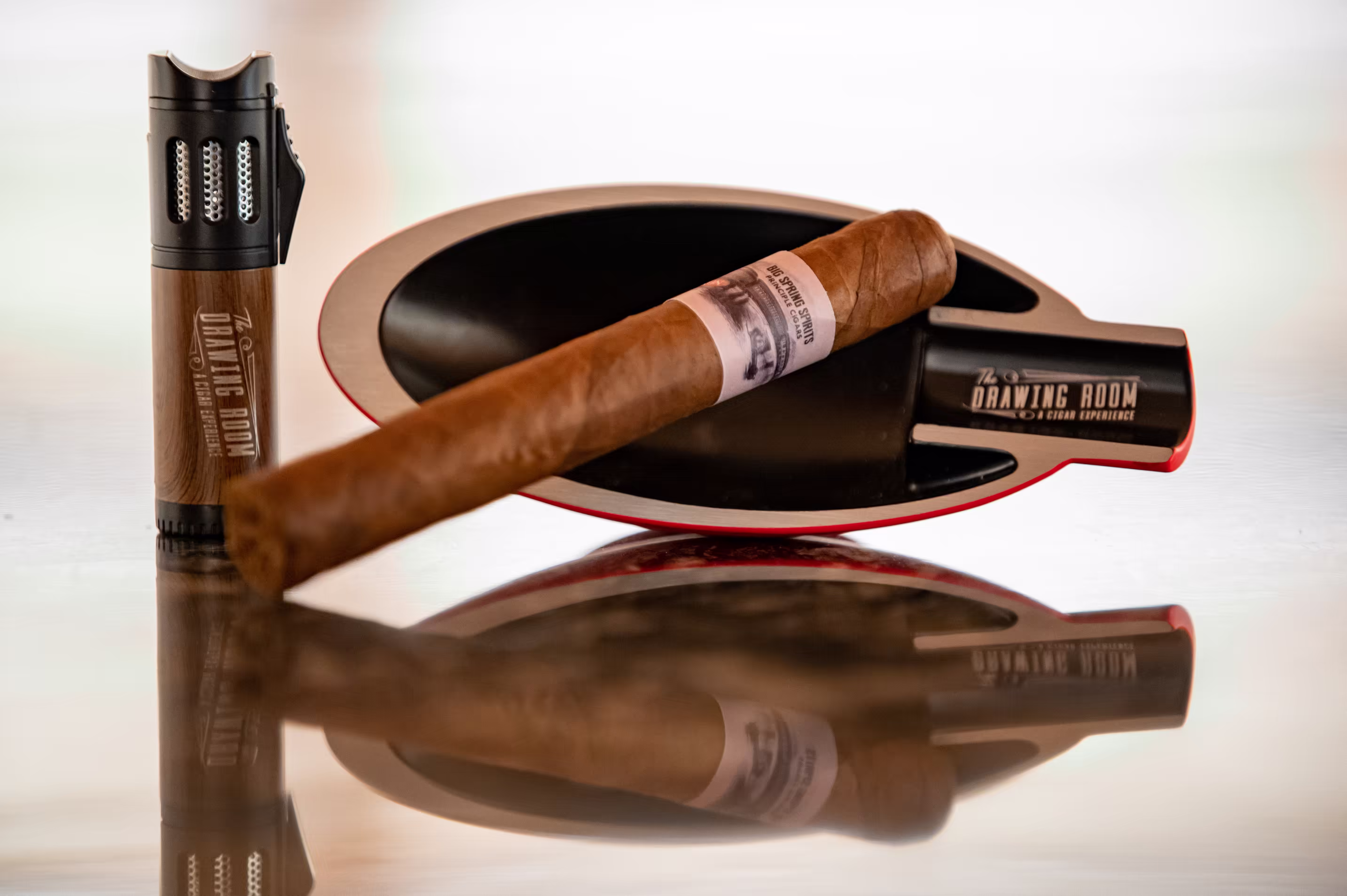 The Drawing Room branded cigar and accessories on white mirror-finish table. Photo by Fisher Fotos