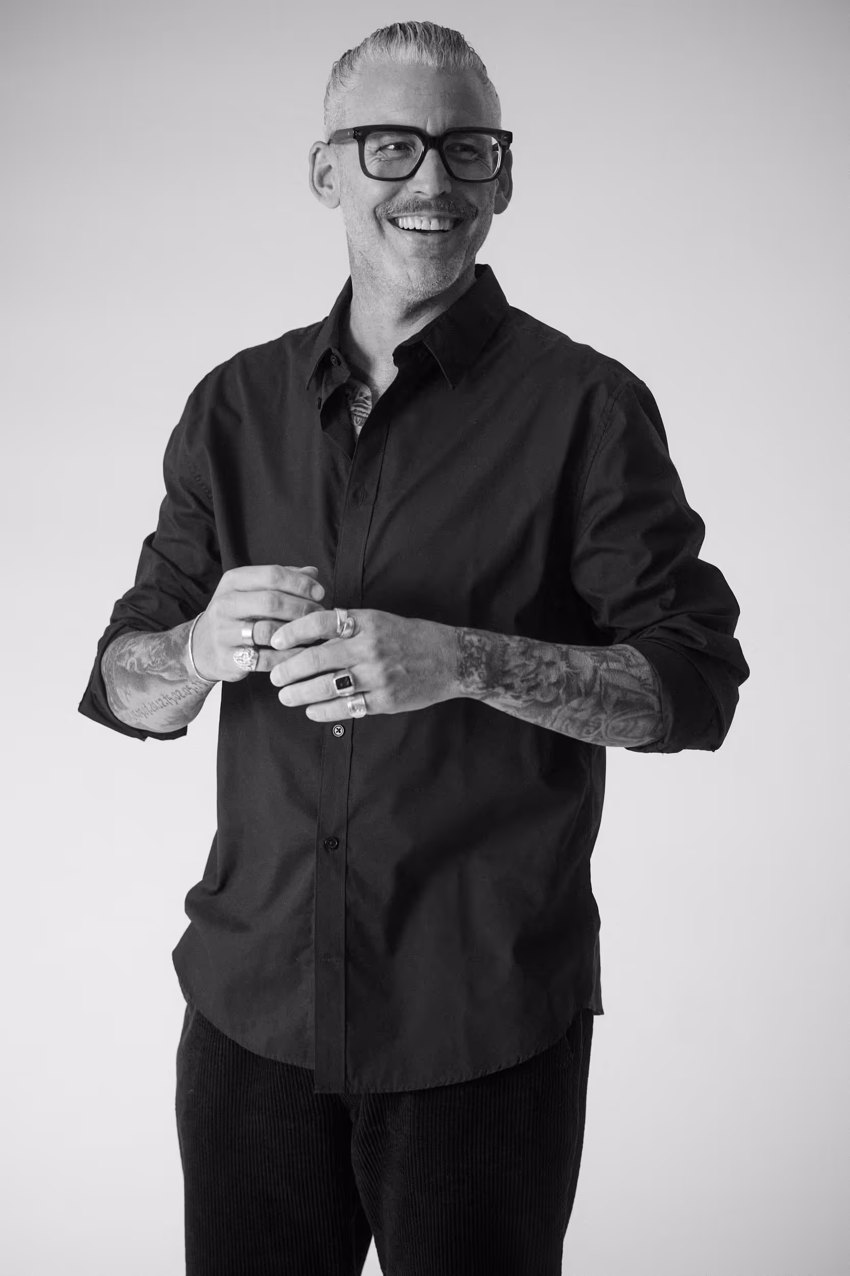 Markus Bauer, CEO der Tasteful Hospitality Agentur, sitzt lächelnd auf einem Stuhl, barfuß und entspannt, mit verschränkten Händen und einer offenen Ausstrahlung.