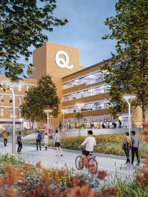 Modernes Mixed-Use-Gebäude mit Backsteinfassade und großem beleuchtetem „Q“, umgeben von Grünflächen, Fußwegen und Menschen, die sich in einem urbanen Platz bewegen und aufhalten.