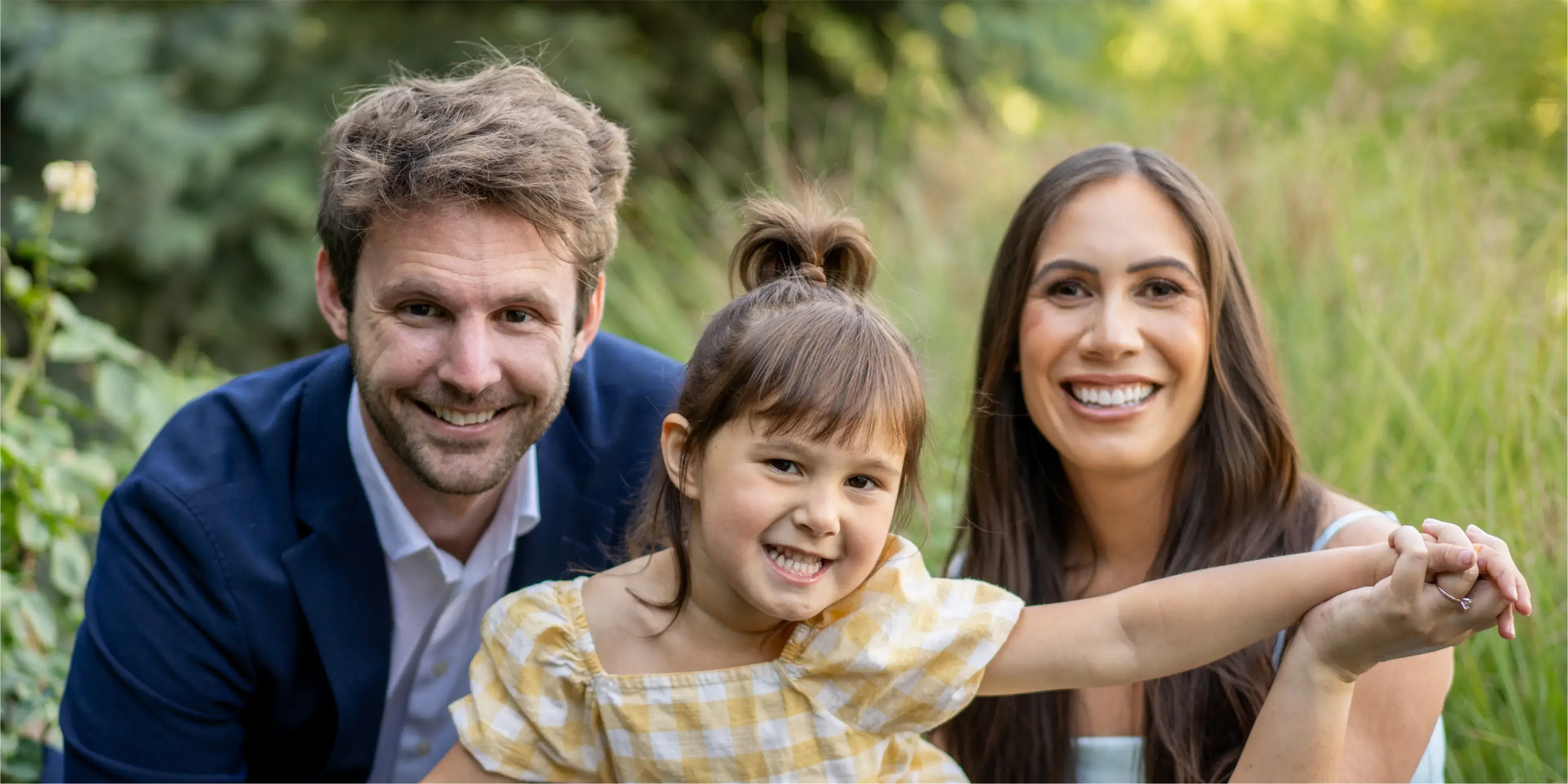 A man and a woman pose for a picture with a little girl.